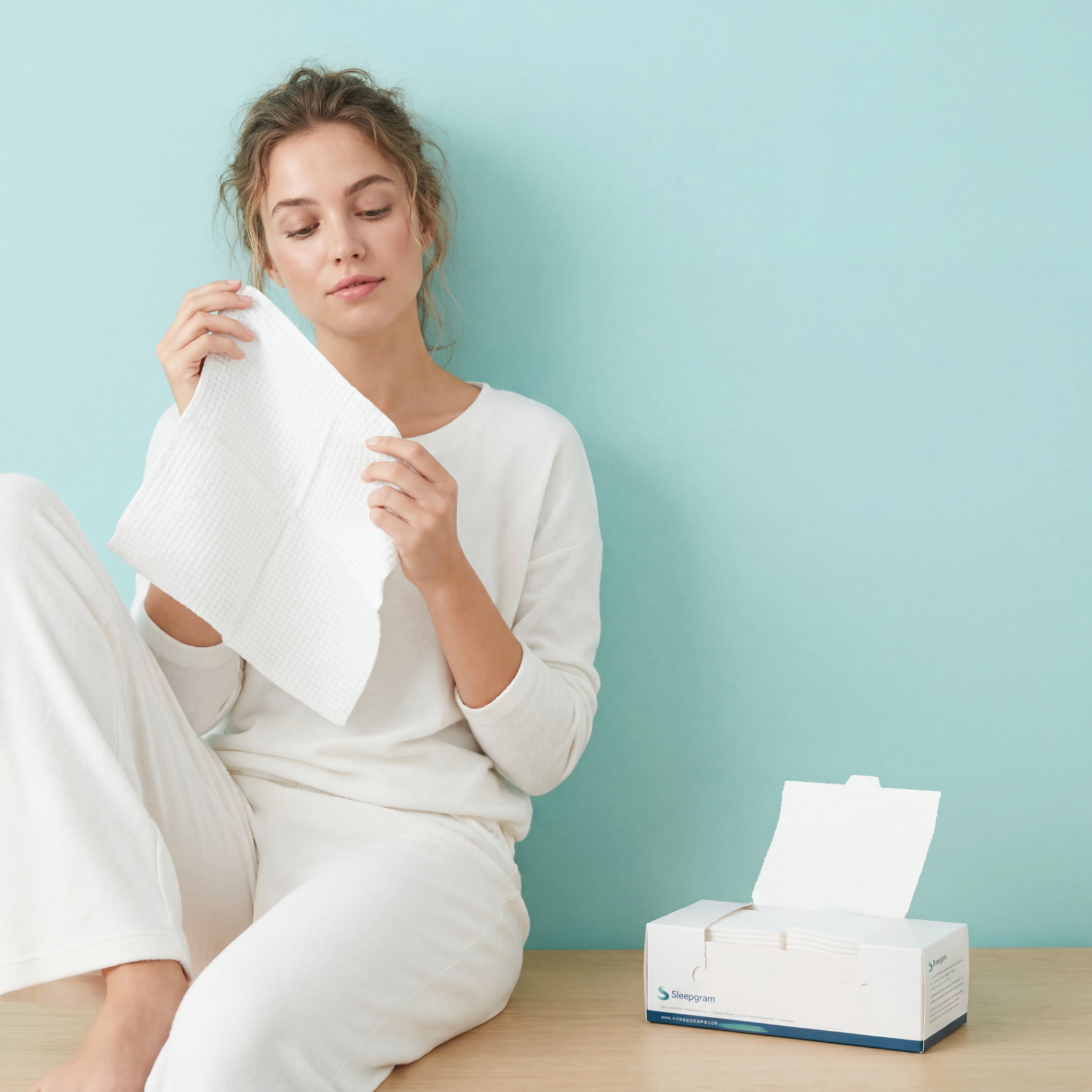 Woman holding a white Sleepgram towel during her skincare routine